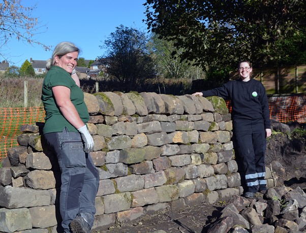 picture of the ranger and apprentice leaning against a stretch of dry stone wall they have built.