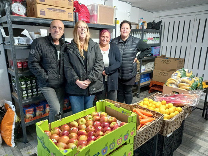 Four volunteers pictured with boxes of fruit and other food in the Hurst Farm Pantry