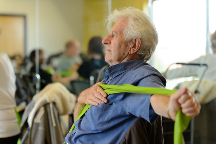 Male participant taking part in a theraband stretch as part of a seated exercise class
